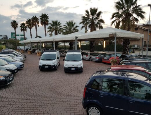 Parcheggio di LUMIKA Goup con furgoni bianchi per autonoleggio e diverse auto. Servizi di noleggio disponibili.