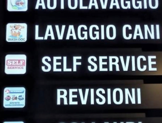 Insegna luminosa con indicazioni di servizi per auto e moto: autolavaggio, lavaggio cani, self service, revisioni e collaudi.