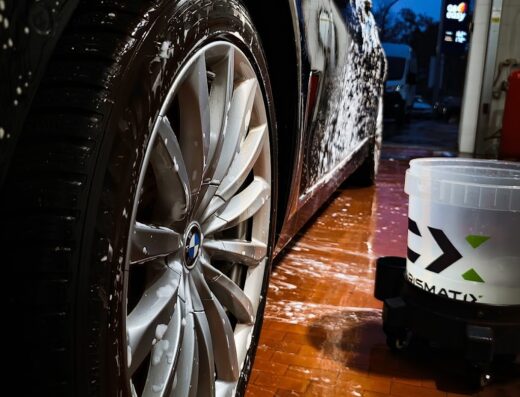 Primo piano di un'auto di lusso nera in fase di lavaggio a mano presso AVANT Autolavaggio, con attenzione ai dettagli della cura della carrozzeria e della pulizia dei cerchi.