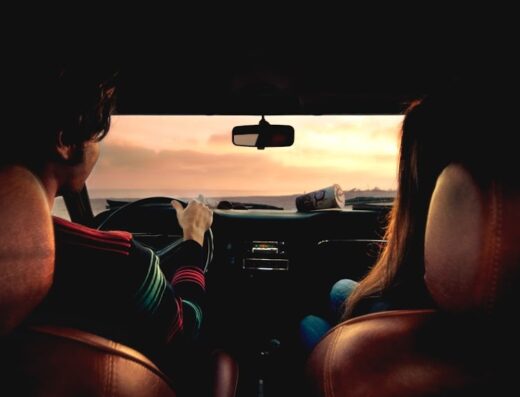 Interno auto con guidatore e passeggero che guardano il tramonto sul mare, ideale per autonoleggio Avis a Belluno per viaggi e vacanze