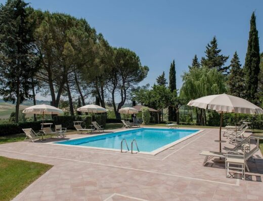 Piscina rilassante con lettini e ombrelloni presso l'Azienda Agricola e Agriturismo Vallorsi, perfetta per una vacanza immersa nel verde.