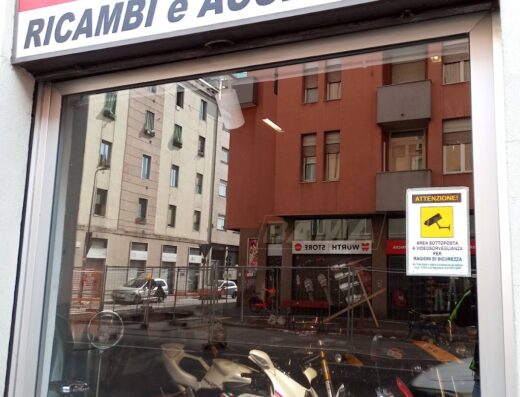 Vetrina di Bama Moto, officina e vendita ricambi e accessori per moto. In esposizione moto Ducati e altri modelli. Cartello videosorveglianza.