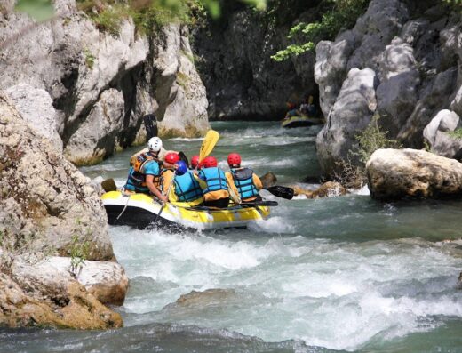 A group of people whitewater rafting on a river in Basilicata, Italy, surrounded by rocky cliffs, showcasing an adventure travel experience.