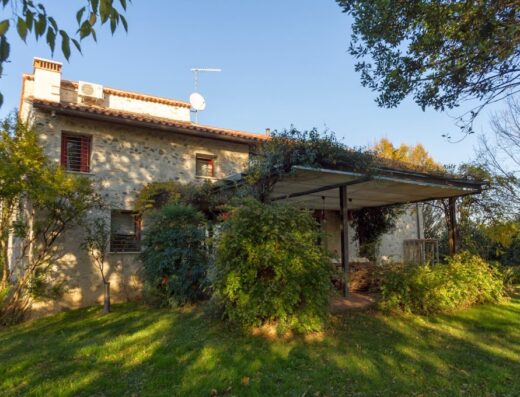 B&B Al Cantico: Esterno di una casa in pietra con tetto in tegole, circondata da vegetazione e prato verde.