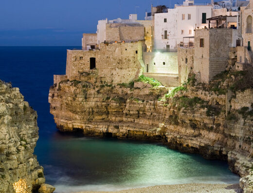 Panoramica notturna di Polignano a Mare, Puglia: scogliere a picco sul mare Adriatico, case bianche a strapiombo, atmosfera suggestiva per un soggiorno indimenticabile a Casa Dorsi.