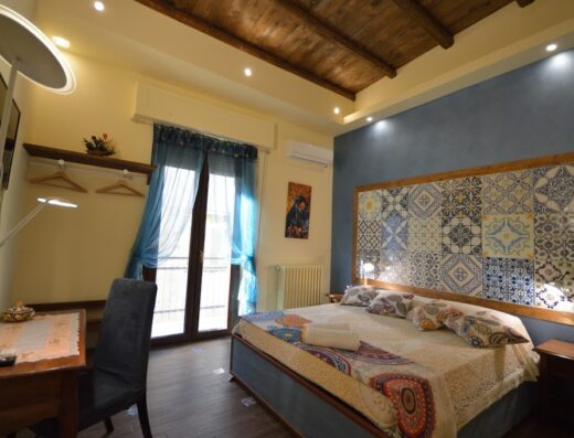 Camera matrimoniale del B&B Centro Sicilia a Enna Centro, con letto decorato con piastrelle siciliane, scrivania e balcone.