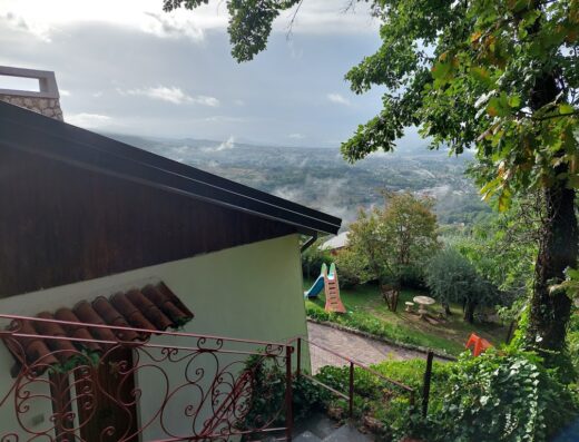 Vista panoramica dal B&B il Querceto, con giardino, area giochi per bambini e paesaggio collinare sullo sfondo.