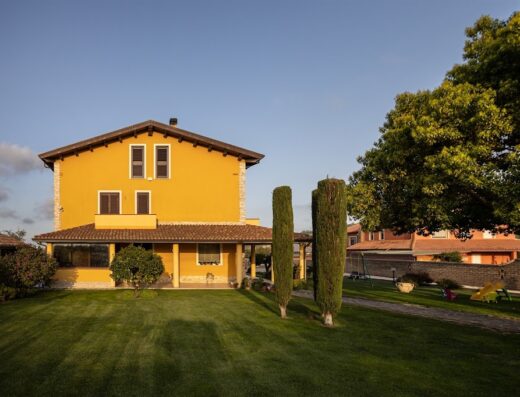 B&B La Canfora Cin: Facciata esterna della struttura con giardino curato, alberi di cipresso e area giochi per bambini.