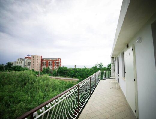 Vista dal balcone di B&B La casa di Chiaretta con vegetazione, ferrovia, edificio residenziale e scorcio di mare all'orizzonte.