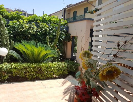 Giardino curato a B&B La Villetta con piante ornamentali, cespugli verdi e recinzione bianca in legno.