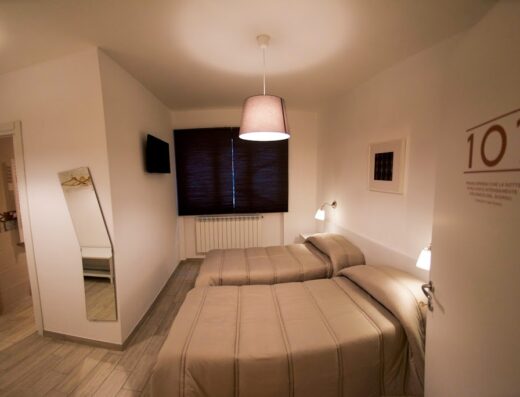 Interno di una camera del B&B Lenotti con due letti singoli, arredamento moderno e minimalista, illuminazione soffusa e porta con numero 101