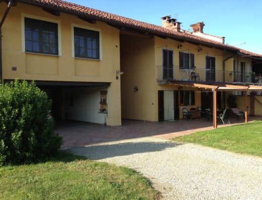 Esterno del B&B Quattro Gatti, una residenza di campagna con facciata gialla, balconi e area esterna attrezzata per il relax.