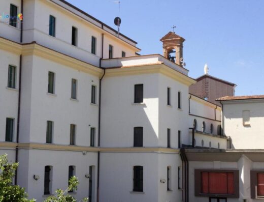 B&B Residenza Montenevoso: Facciata esterna dell'edificio con finestre, torre campanaria e statua religiosa sullo sfondo, architettura tipica italiana per un soggiorno indimenticabile.