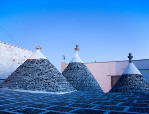 Vista dei caratteristici tetti a cono dei trulli pugliesi, costruiti in pietra locale, sotto un cielo blu sereno. Architettura tradizionale italiana.