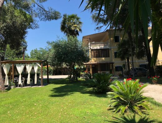 B&B Villa Berghella: Esterno della villa con ampio giardino, gazebo con tende bianche, vegetazione curata e auto parcheggiata. Ideale per un soggiorno rilassante.