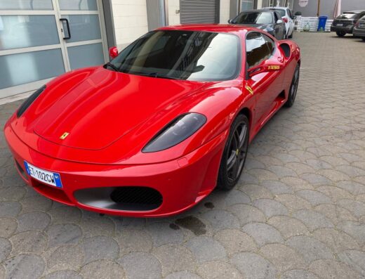Ferrari F430 rossa lucida in primo piano presso Beauty Car Lombardo Autolavaggio a Mano, dettaglio della carrozzeria e dei cerchi.