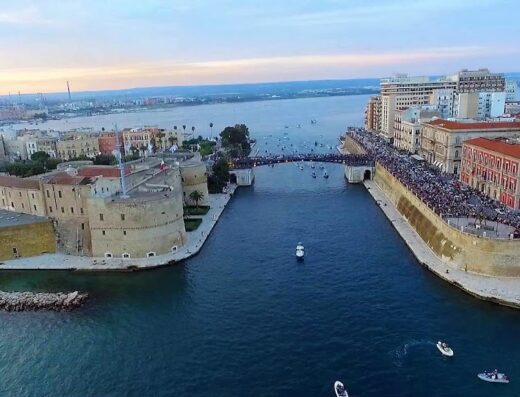 Vista aerea del Castello Aragonese di Taranto e del canale navigabile con folla di persone e imbarcazioni, ideale per un bed and breakfast Il Subacqueo