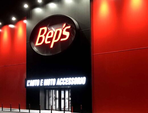 Foto notturna del negozio Bep's a Modena, specializzato in accessori per auto e moto, con insegna luminosa ben visibile e ingresso illuminato.