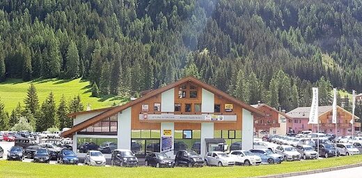 Bernard Claudio Motors showroom featuring motoslitte, ATV Quad, BRP, Can Am, snow frese, officina, and Suzuki Point with mountain backdrop.