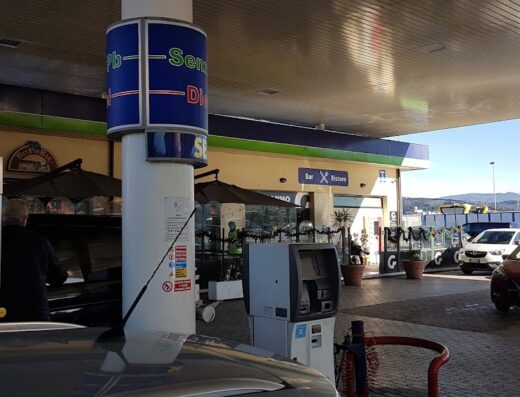 Stazione di servizio Beyfin con pompe di benzina, area ristoro e parcheggio auto in una giornata soleggiata, ideale per viaggi in moto e rifornimento.