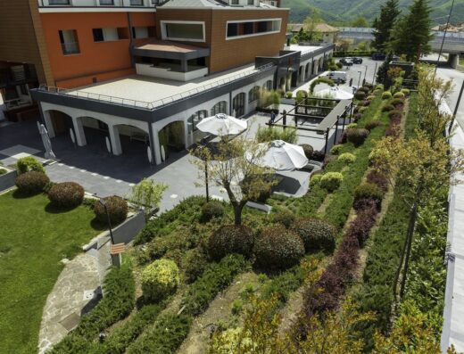 Vista panoramica del BHOTEL, con giardini curati, ombrelloni bianchi e architettura moderna. Ideale per viaggi e relax.