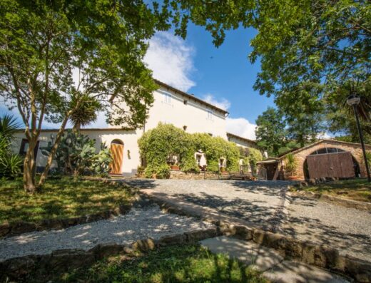 Bike Hotel Massa Vecchia, an inviting Tuscan villa with stone driveway, lush greenery, and a dedicated bike storage area for cycling enthusiasts.