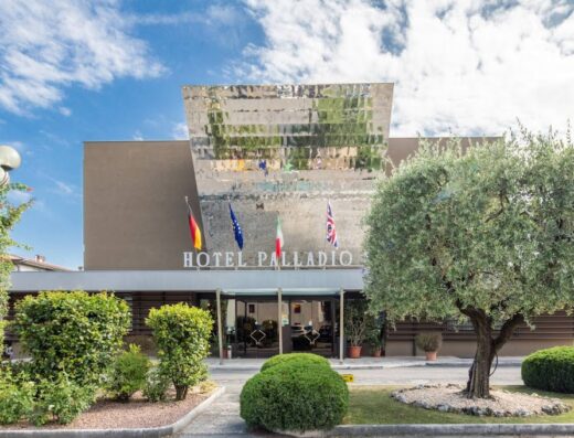 Bonotto Hotel Palladio: Facciata dell'hotel con insegna, bandiere di diverse nazioni e vegetazione curata, per un'accoglienza di lusso a Padova.