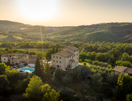 Vista aerea del Borgo Castello Panicaglia, una location di lusso con piscina immersa nel verde delle colline toscane, ideale per vacanze e viaggi in moto.