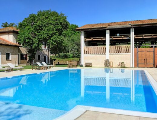 Piscina azzurra e architettura rurale al Borgo Pallavicini Mori, location ideale per motociclisti in viaggio e relax.