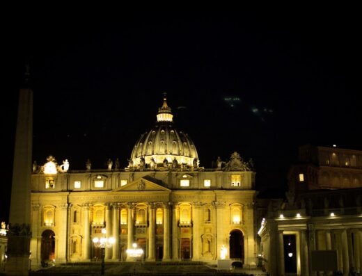 St. Peter's Basilica illuminated at night in Vatican City, near Borgo Pio Suites Inn, showing the dome and obelisk.