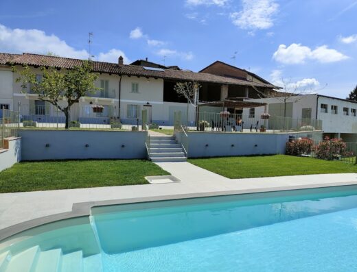 Bricco Bed&bike: vista esterna della struttura con piscina, prato verde curato e area relax con tavoli e sedie. Ideale per motociclisti in viaggio.