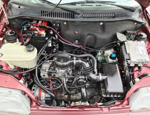 Dettaglio del motore di un'auto Brillanti Car, con batteria, tubi e componenti ben visibili. Manutenzione e ricambi auto.