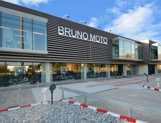 Facciata moderna di Bruno Moto, concessionaria di moto con vetrine che espongono modelli Kawasaki e Yamaha, design architettonico contemporaneo.