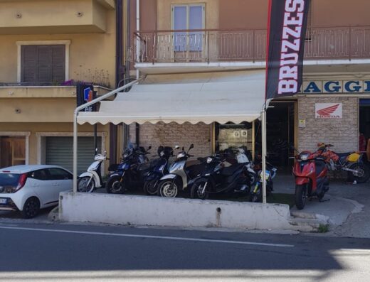 Bruzzese Moto: esposizione di scooter e moto in vendita presso il concessionario, con bandiera del marchio ben visibile.