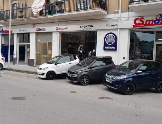 C.S. Motors S.n.c. di Simone Perricone S. e C.: esposizione di ciclomotori Aixam di vari colori davanti alla concessionaria di moto e ricambi.