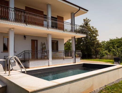 Ca' del Viaggiatore: Vista di una piscina rettangolare con scala in acciaio, situata di fronte a una casa a due piani con balconi in ferro battuto. Un'oasi di relax per viaggiatori.