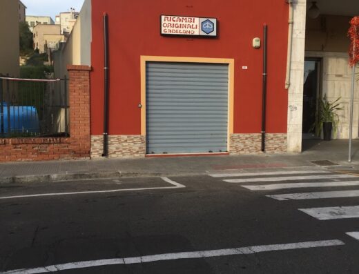 Ingresso del negozio Ricambi Originali Cadelano, specializzato in accessori e ricambi per moto, con saracinesca grigia chiusa.