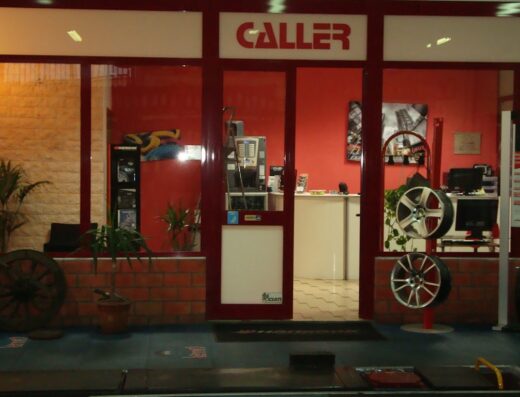 Ingresso del negozio Caller, specializzato in servizi per moto e accessori, con esposizione di cerchi in lega e interni visibili.