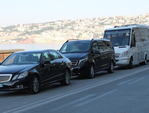 Cammarota Viaggi: Servizio bus e limousine con Mercedes, van e minibus parcheggiati lungo la costa di Napoli. Trasporto turistico di lusso.