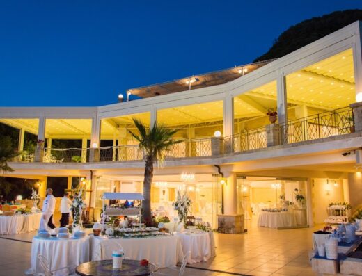 CapoSperone Resort: Elegante location per eventi serali con buffet allestiti, tavoli imbanditi e architettura illuminata, ideale per matrimoni e celebrazioni speciali.