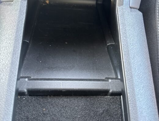 Interno di un'auto che mostra lo scomparto portaoggetti della console centrale che necessita di pulizia presso il Car Beauty Center di Gino.