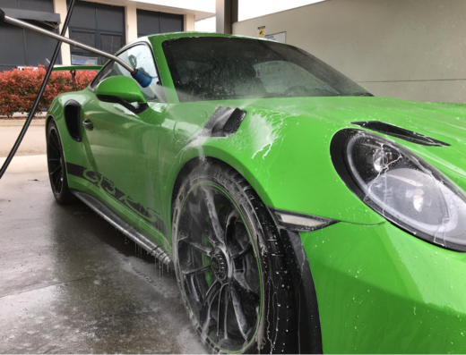 Lavaggio auto full service a Mestre: Dettaglio di una Porsche verde brillante in fase di pulizia con idropulitrice, servizio professionale per la cura dell'auto.