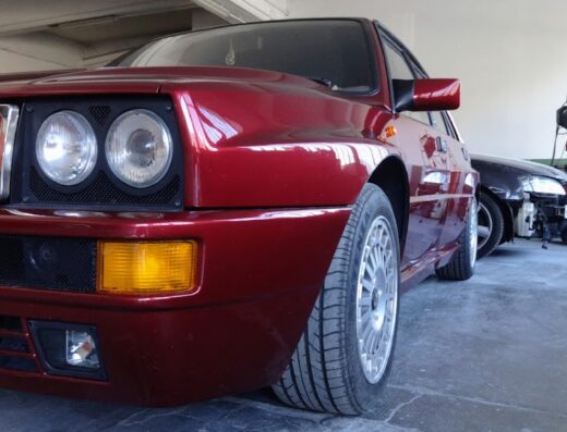 Dettaglio frontale di una Lancia Delta Integrale rossa in riparazione presso Carrozzeria Garage 76, officina specializzata in restauro auto d'epoca.