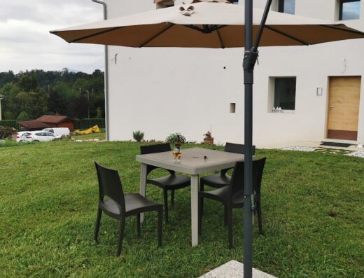 Area relax all'aperto presso Casa Borriero Farmhouse Charme B&B con tavolo, sedie e ombrellone in giardino. Ideale per vacanze rilassanti.