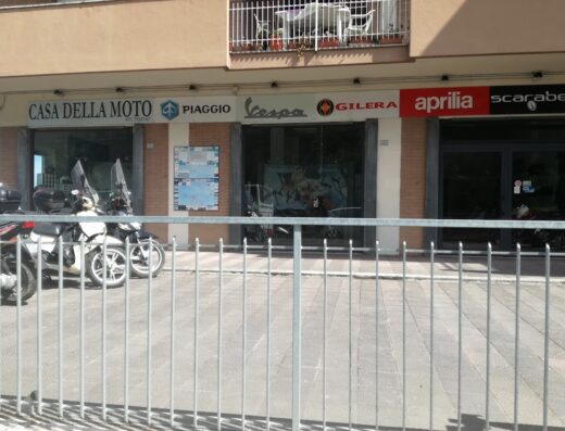 Foto della facciata di Casa della Moto, rivenditore di moto Piaggio, Vespa, Gilera, Aprilia e Scarabeo. Motocicli parcheggiati di fronte.