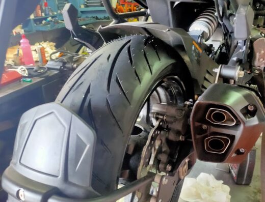 Dettaglio della parte posteriore di una moto: pneumatico, marmitta e sistema frenante. Servizi di riparazione e manutenzione moto.