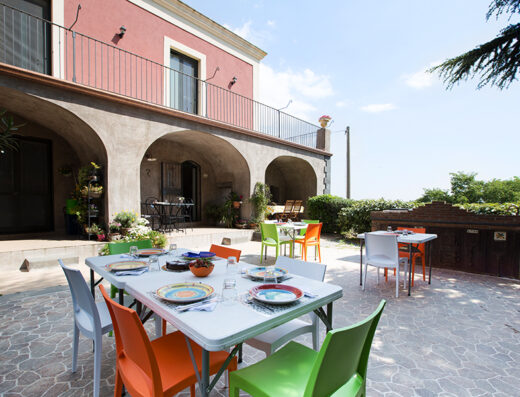Casale Poggio del Tiglio: Tavolo apparecchiato all'aperto con sedie colorate, ideale per un pranzo conviviale in un'atmosfera rilassante.