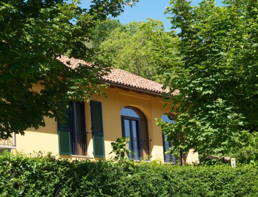 Cascina Ghitin Relais: Facciata esterna con finestre ad arco e persiane verdi, immersa nel verde della campagna italiana. Un'oasi di relax per motociclisti in viaggio.