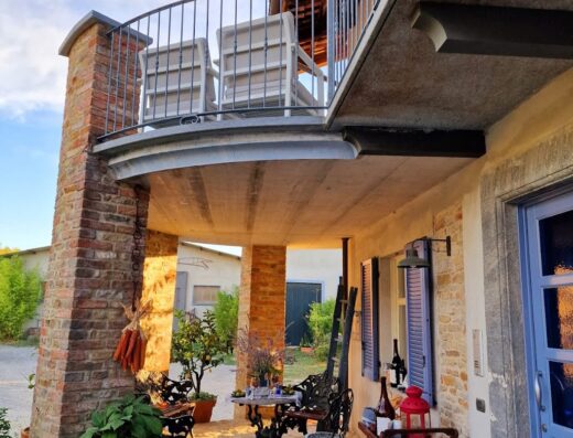 Terrazza accogliente a Cascina Giardini B&B, Italia. Tavolo con sedie in ferro battuto, ideale per relax e degustazione vini.