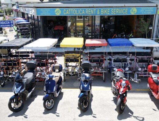 Cattolica Rent: esposizione di scooter, risciò a pedali con copertura colorata e golf cart presso il negozio di noleggio moto e bici a Cattolica.